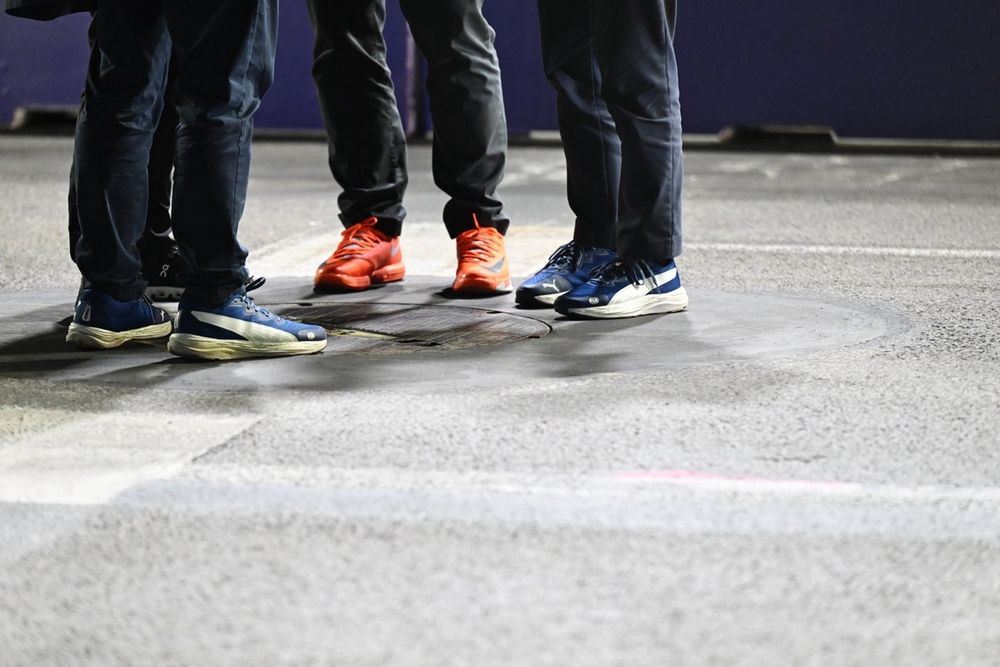 Los comisarios y el personal del circuito se reúnen para revisar una tapa de alcantarilla en la pista que provocó una bandera roja.