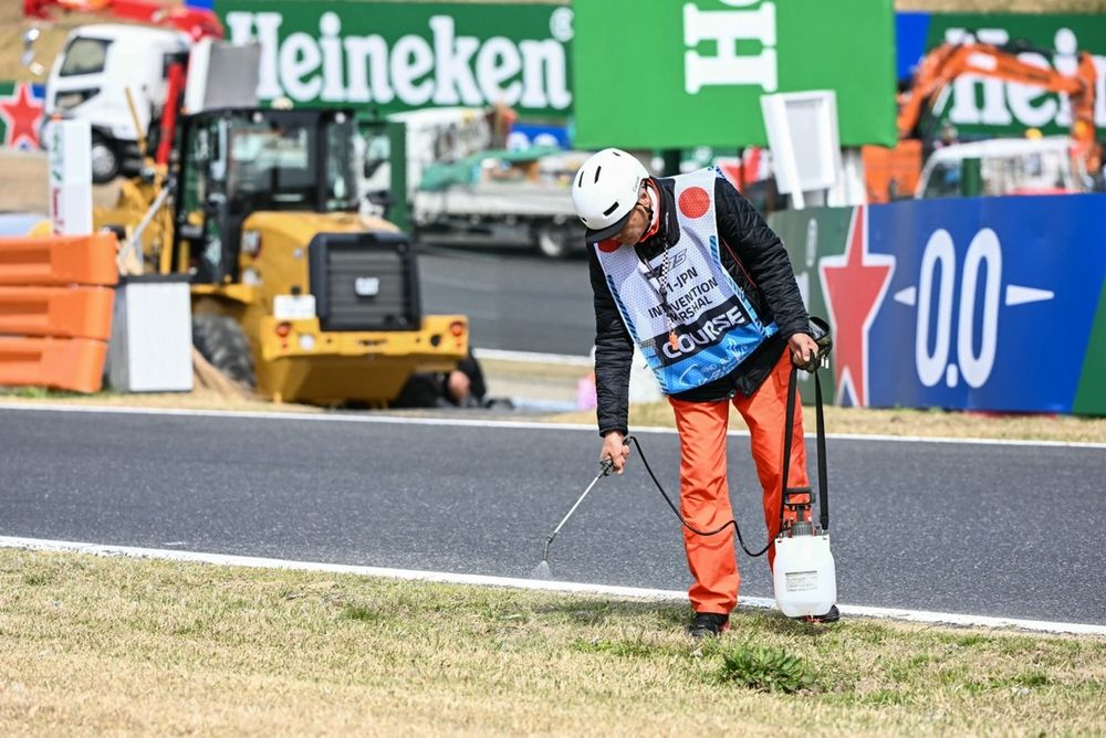 Un commissaire humidifie la pelouse pour prévenir le risque d'incendie lors du samedi au Grand Prix du Japon 2025 de F1.