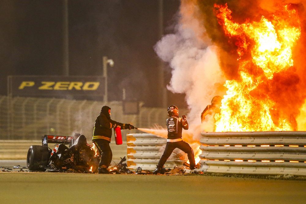 Fire marshals deal with the flames and a medical delegate assists Romain Grosjean, Haas F1, after a huge crash on the opening lap
