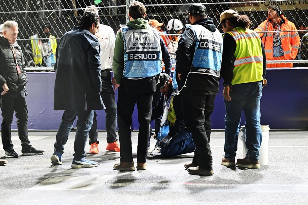 Los comisarios y el personal del circuito se reúnen para revisar una tapa de alcantarilla en la pista que provocó una bandera roja.