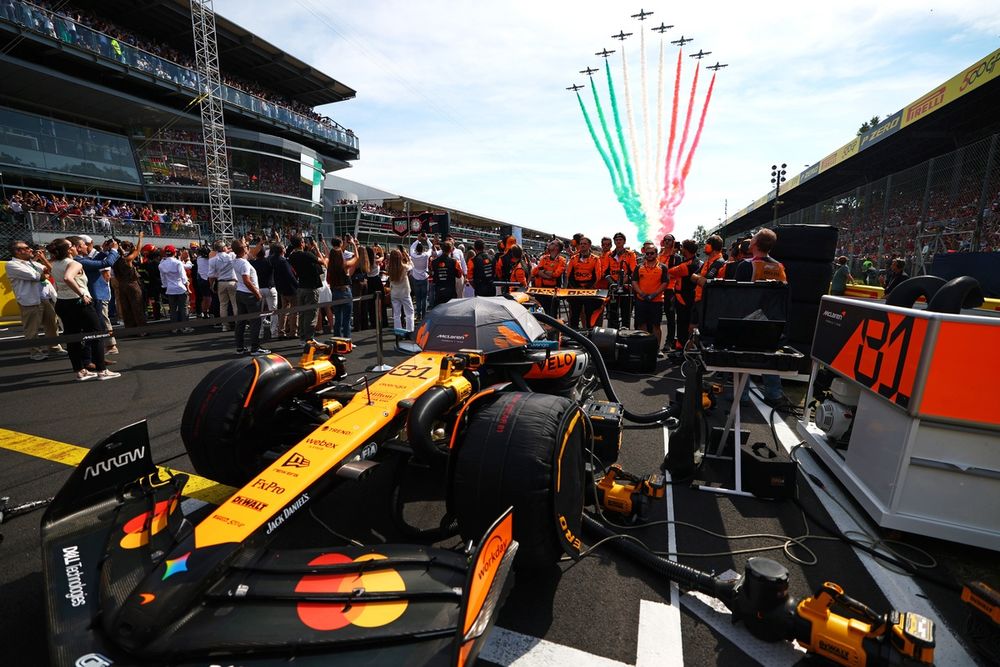 Team members of McLaren stand on the grid